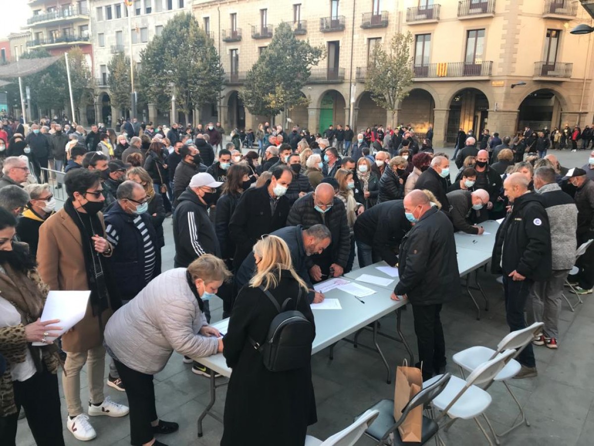 Un grup de persones firma el manifest de la plataforma «Manlleu diu prou» a la concentració de diumenge a la plaça Fra Bernadí