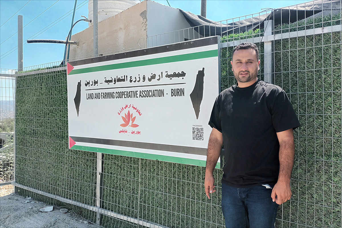 Ghassan Najar, un dels fundadors de la cooperativa Land and Farming, davant d'un cartell a l'entrada de la cooperativa